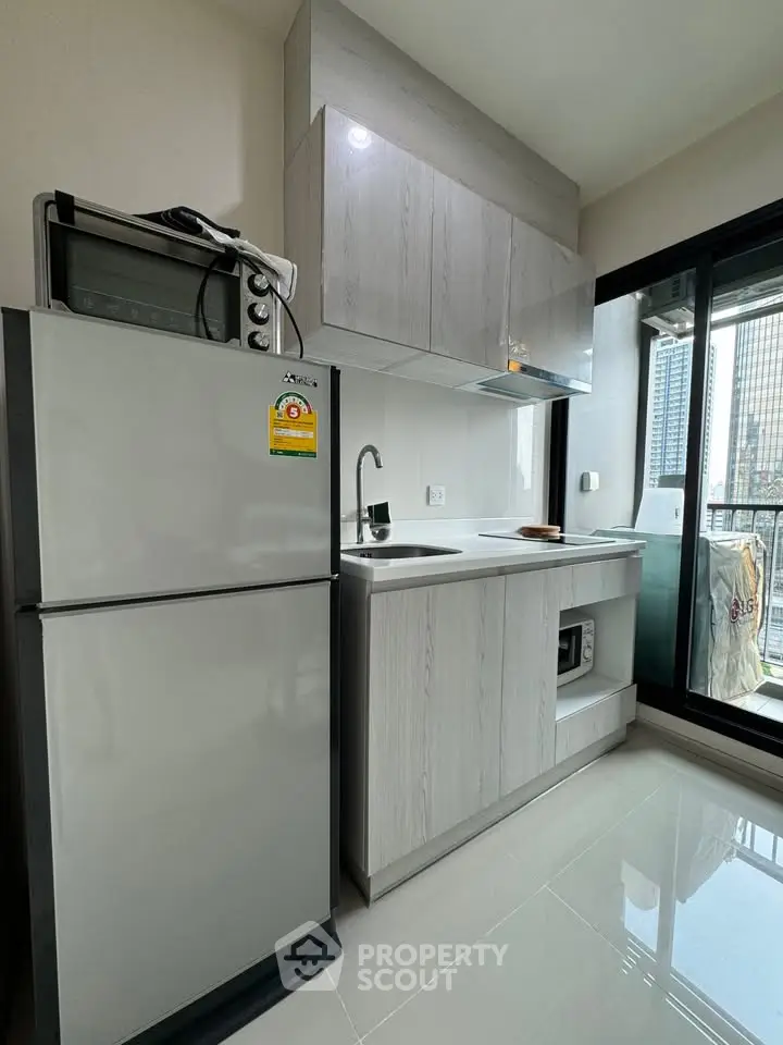 Modern kitchen with sleek cabinets and balcony view in urban apartment