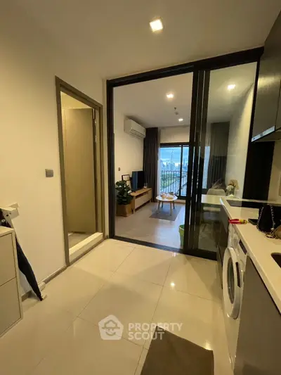 Modern apartment with open layout, featuring a cozy living room and kitchen with washing machine.