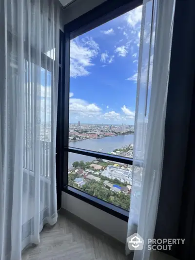 Stunning river view from high-rise apartment window with sheer curtains