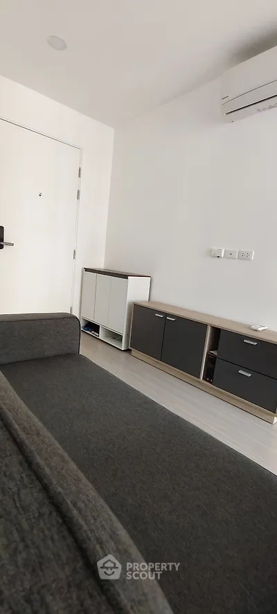 Modern living room with sleek furniture and air conditioning unit, showcasing minimalist design.