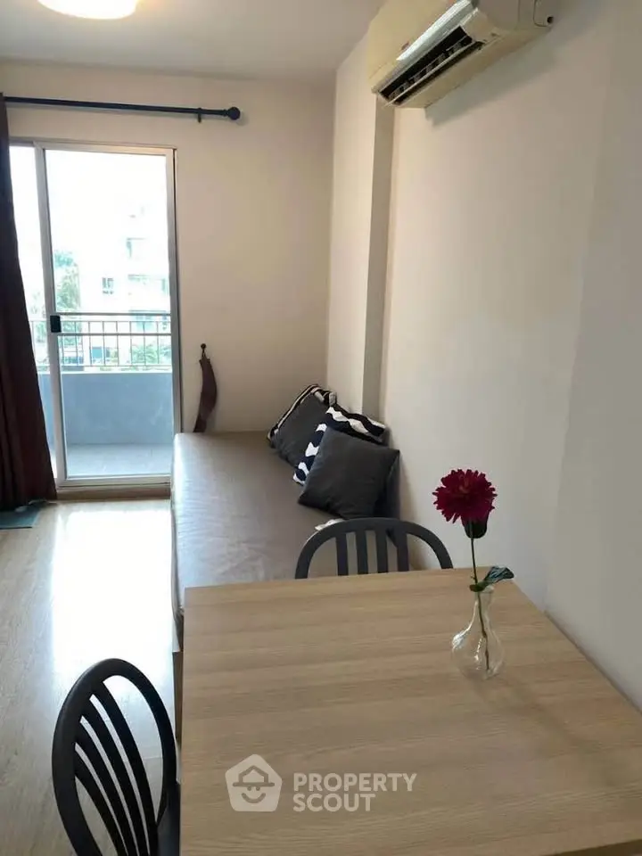 Cozy living room with balcony access and modern dining area in a stylish apartment.