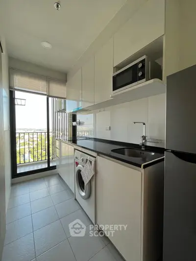 Modern kitchen with sleek appliances and balcony view in a stylish apartment.