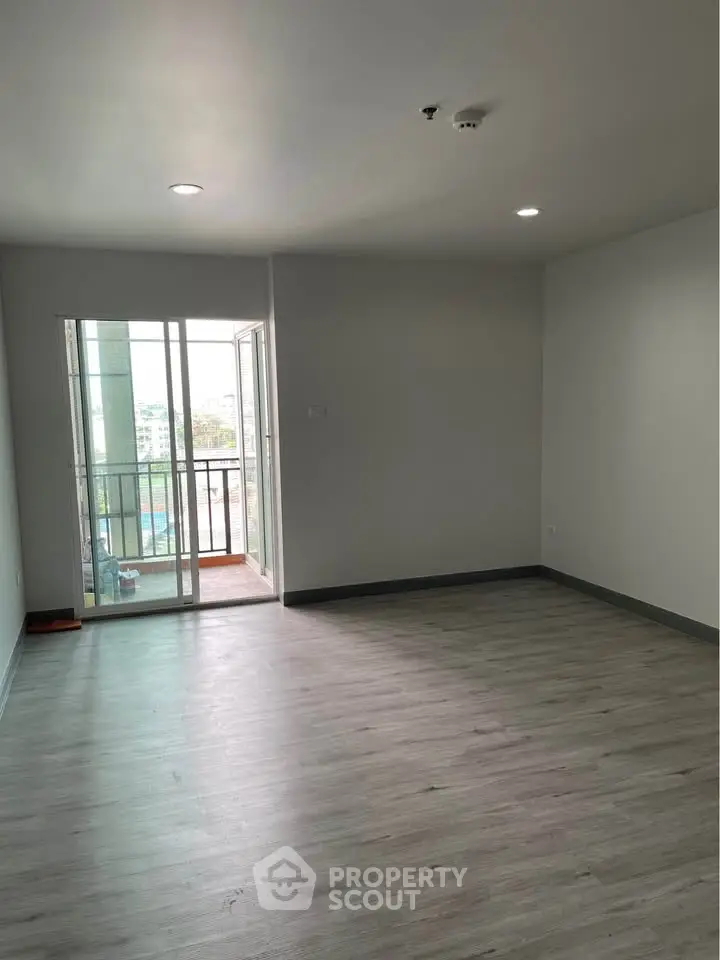 Spacious empty living room with balcony access and modern flooring.