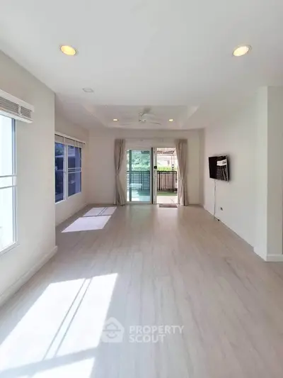 Spacious living room with large windows and balcony access, perfect for natural light lovers.