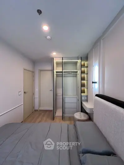 Modern bedroom with open wardrobe and stylish lighting in a cozy apartment.