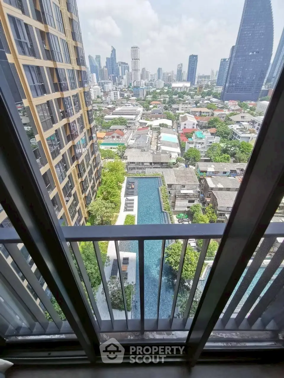 Stunning cityscape view from high-rise balcony overlooking pool and skyline.