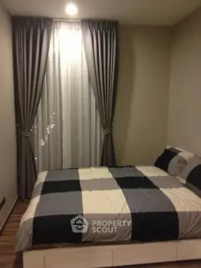 Cozy bedroom with stylish curtains and modern bedding in a contemporary apartment.
