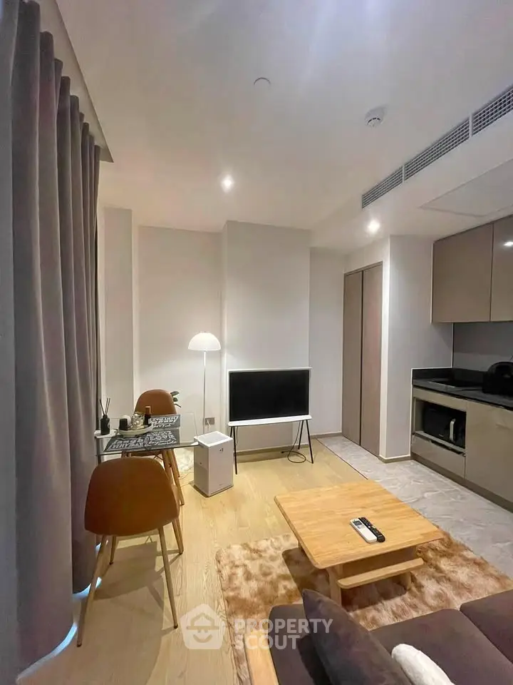 Modern living room with sleek kitchen, cozy seating, and stylish decor in a contemporary apartment.