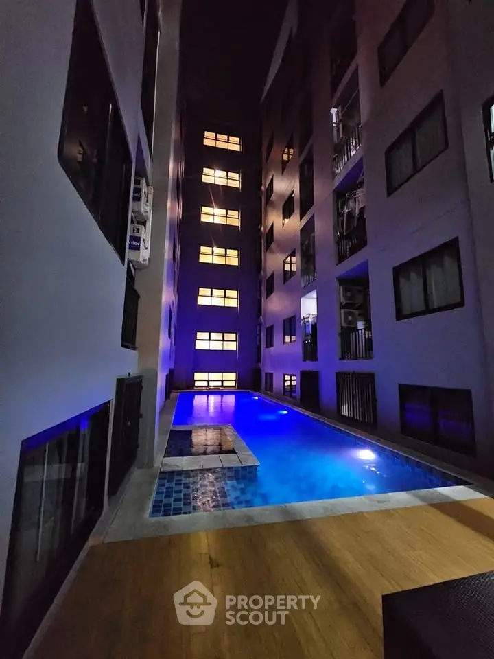 Modern apartment building with illuminated pool at night, showcasing luxury urban living.