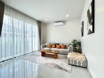 Modern living room with large windows, stylish decor, and cozy seating area.