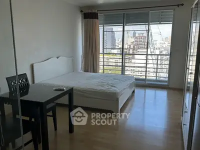Spacious bedroom with city view and modern furnishings in high-rise apartment.