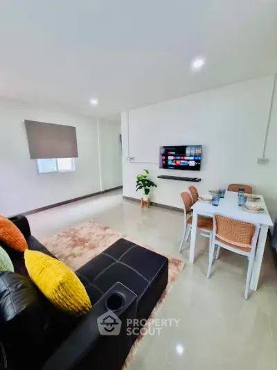 Modern living room with cozy dining area and wall-mounted TV, perfect for entertaining.