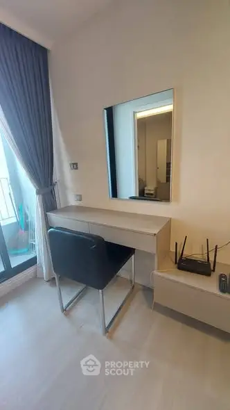 Modern study area with sleek desk, chair, and mirror near a window with blue curtains.