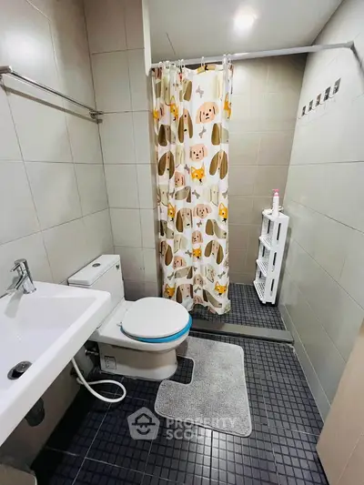 Modern bathroom with shower curtain, sink, and toilet in a tiled setting.