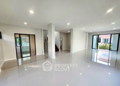 Spacious modern living room with glossy tile flooring and large windows for natural light.