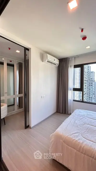 Modern bedroom with large windows and city view, featuring a cozy bed and air conditioning.