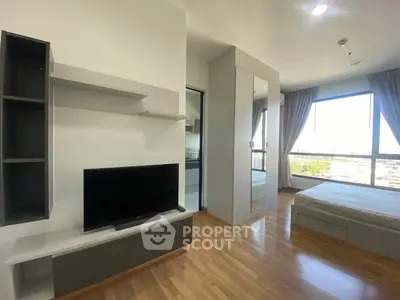 Modern bedroom with large window and sleek furniture in a bright apartment.