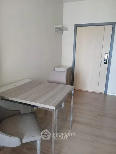 Spacious and well-lit living room with modern wooden flooring, elegant dining table set, and a sleek air conditioning unit, perfect for comfortable urban living.