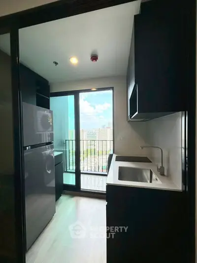 Modern kitchen with sleek black cabinets and city view from balcony.