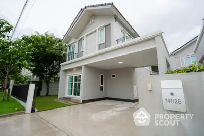 Modern two-story house with driveway and lush greenery in a serene neighborhood.