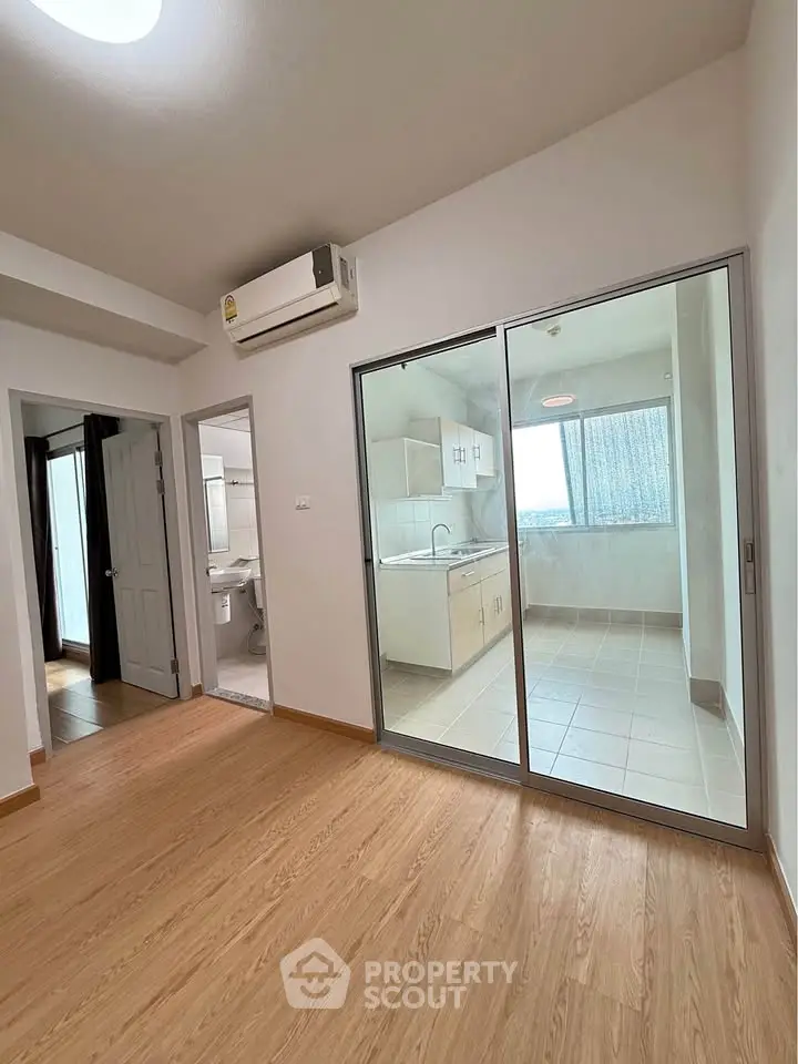 Modern apartment with open kitchen and wooden flooring, featuring a sliding glass door.