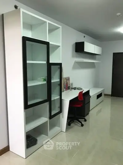Modern study room with sleek white furniture and red chair, perfect for productivity and style.