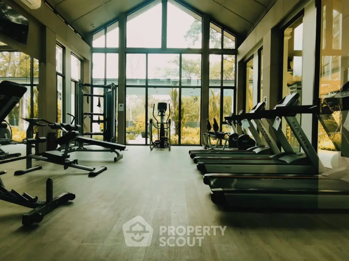 Spacious modern gym with large windows and state-of-the-art equipment in luxury real estate property.