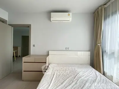 Modern bedroom with air conditioning and natural light, featuring sleek furniture and neutral tones.