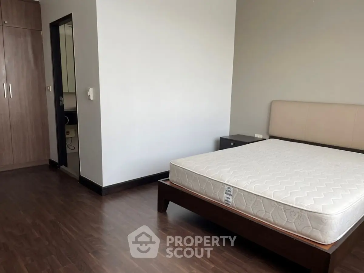 Spacious bedroom with wooden flooring and modern furnishings in a stylish apartment.