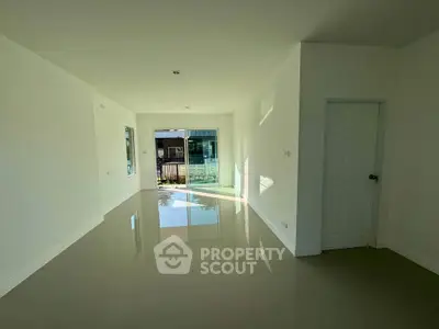 Spacious empty living room with glossy floors and large windows for natural light.