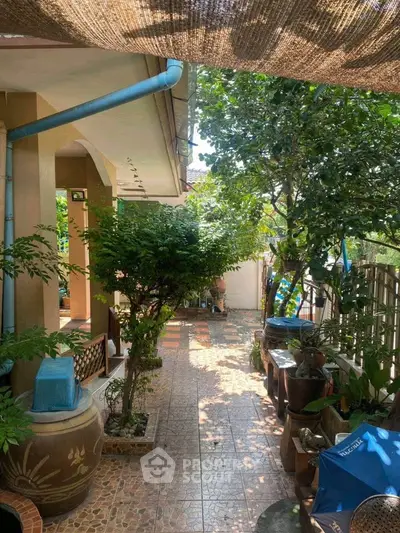 Charming garden patio with lush greenery and tiled flooring, perfect for outdoor relaxation.