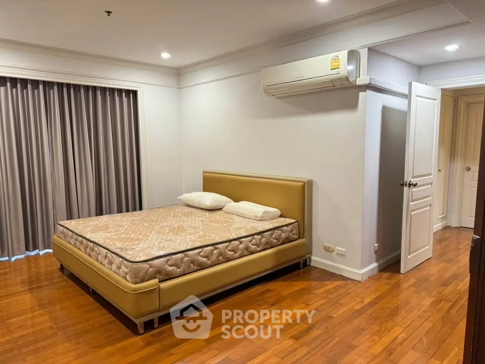 Spacious bedroom with elegant wooden flooring and modern air conditioning unit.