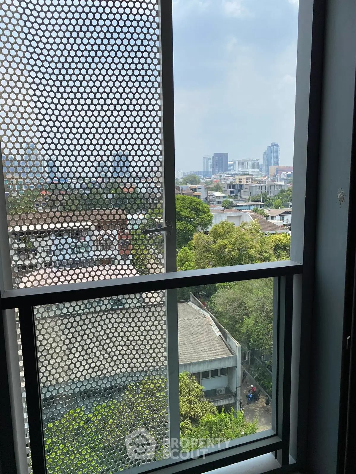 Stunning cityscape view from a high-rise window, showcasing urban skyline and lush greenery.