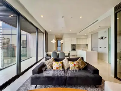 Luxurious modern living room with floor-to-ceiling windows and open kitchen in high-rise apartment.