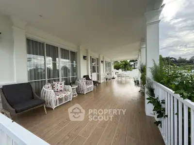 Spacious covered balcony with elegant wicker furniture and scenic views, perfect for relaxation and entertaining.