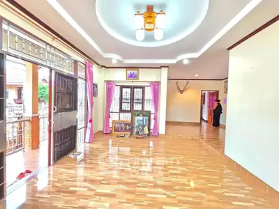 Spacious living room with wooden flooring and elegant ceiling lights, perfect for family gatherings.