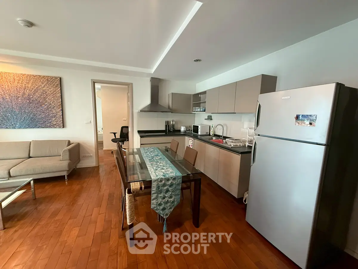 Modern open-layout kitchen and living area with wooden flooring and stylish decor.
