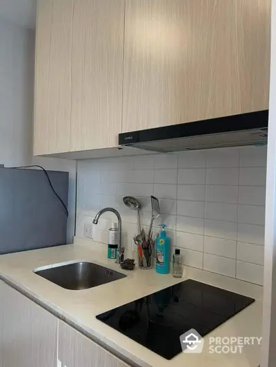 Modern kitchen with sleek cabinetry and electric cooktop in compact layout.