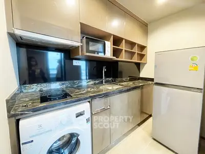 Modern kitchen with sleek cabinets, washing machine, and stainless steel appliances