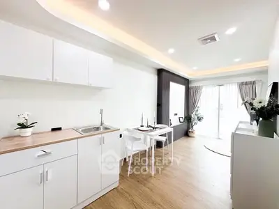 Modern open-layout kitchen and dining area with sleek white cabinets and natural light.