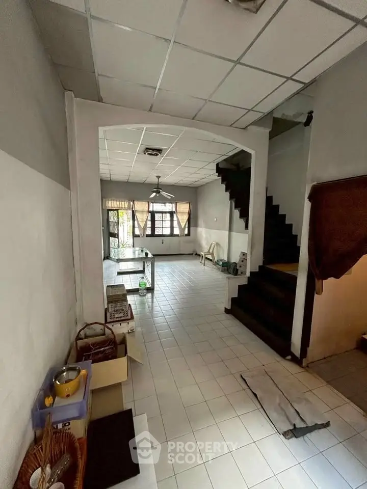 Spacious open-plan living area with tiled flooring and staircase, ideal for customization.