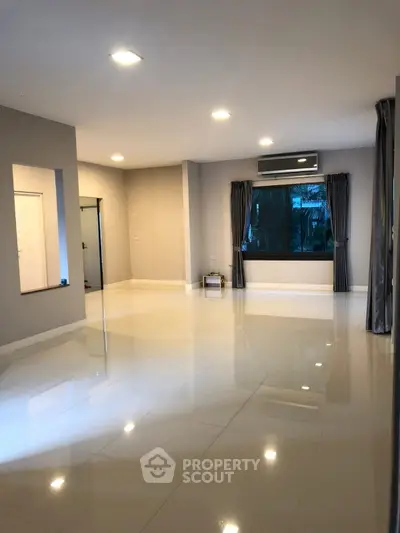 Spacious modern living room with large windows and glossy tiled floors