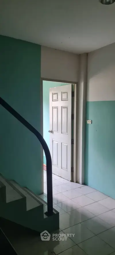 Bright interior hallway with open door and staircase, showcasing potential for renovation.