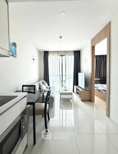 Modern open-plan living room with sleek kitchen and large windows offering natural light.