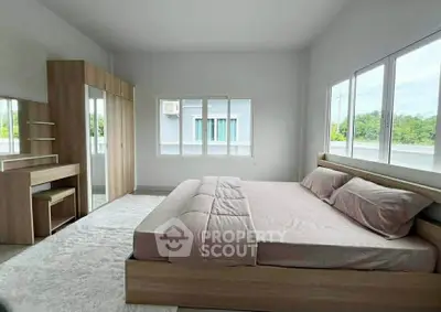 Spacious bedroom with large windows and modern wooden furniture, offering a serene and bright atmosphere.