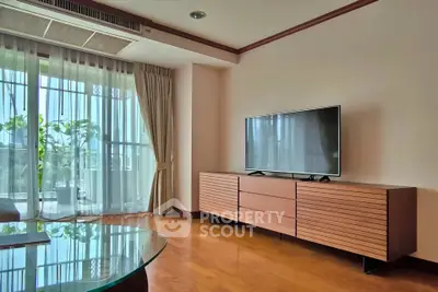 Spacious living room with modern TV setup and large window view