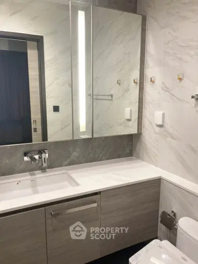 Modern bathroom with sleek vanity and large mirror in luxury apartment.