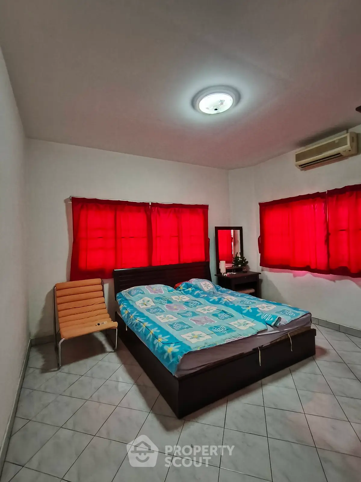 Cozy bedroom with vibrant red curtains and modern furnishings, perfect for relaxation.