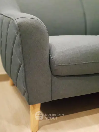 Modern gray sofa with wooden legs in stylish living room interior