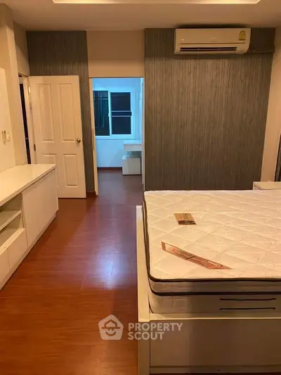 Spacious bedroom with modern design and wooden flooring, featuring air conditioning and ample storage.